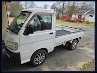 a small white truck parked in front of a garage