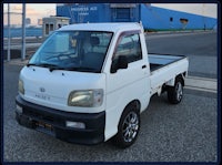 a small white truck parked in front of a ship