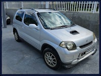 a silver suzuki vitara parked in front of a fence