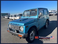 a blue suzuki samurai parked in a parking lot